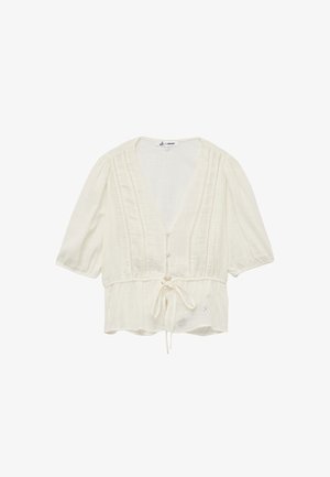 Hvid, tekstureret bluse med dyb V-hals, korte pufærmer, knaplukning fortil og snoreliv. Har detaljer med broderi i øjeform.