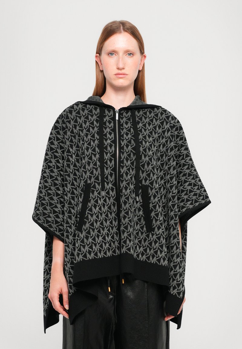 Black and gray poncho with a zip front, featuring a repeated logo pattern, two front pockets, and a hood. It has a soft texture and relaxed fit.