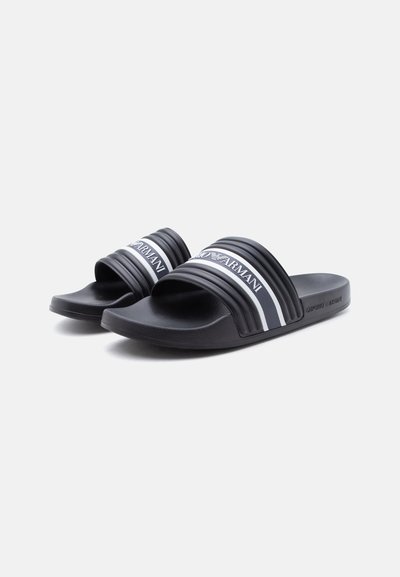 Μαύρες σαγιονάρες με υφασμένα πέλματα και λευκές ρίγες στις κορδέλες, με το λογότυπο Emporio Armani στα πάνω λουράκια.