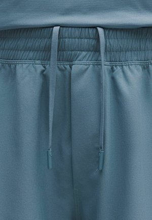 Jasnoniebieskie spodenki sportowe z elastycznym paskiem na talii z sznurkami, gładką teksturą i subtelnymi detalami szwów.