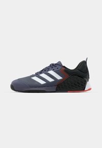 Purple athletic shoe featuring mesh upper, three white stripes, padded collar, black and red accents, textured sole, and rubber outsole.