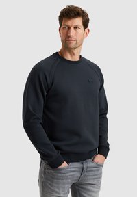Donkerblauwe sweatshirt met een ronde hals, ribgebreide manchetten en taille. Bevat een klein, gestructureerd label op de borst en een gladde stof.