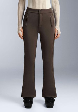 Pantaloni marroni a zampa d'elefante in un tessuto elastico, con due tasche con zip, un dettaglio sulla cucitura frontale e una texture liscia.