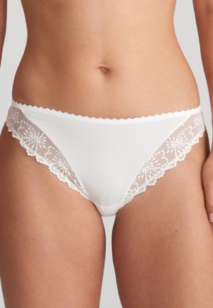 Biancheria intima stile bikini bianca con pannelli in pizzo floreale indossata da una persona, che mostra la vita e la parte superiore delle cosce su uno sfondo neutro.