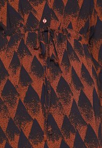 Robe présentant un motif géométrique dans des teintes d'orange brûlé et de bleu marine. Fabriquée en tissu léger avec une taille nouée et des détails de boutons.