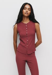 Maroon texturerad ärmlös topp med rund halsringning och knappar framtill; kombinerad med matchande åtsittande byxor. Slät material, avslappnad design.