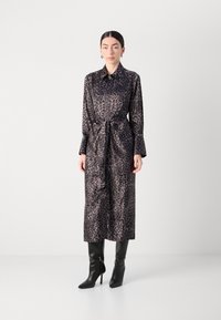 Abito a stampa leopardata in materiale setoso, maniche lunghe, chiusura a bottoni sul davanti, cintura in vita e silhouette fino al ginocchio. Abbinate a stivali neri al ginocchio.
