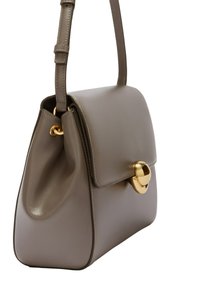 Sac à main en cuir gris avec un design structuré, fermeture à rabat supérieur et un accent en matériel doré circulaire. Bandoulière réglable.