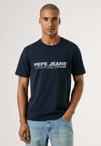 Navyblauwe katoenen t-shirt met een witte logo "PEPE JEANS LONDON" op de voorkant. Korte mouwen en een klassiek ronde hals ontwerp.
