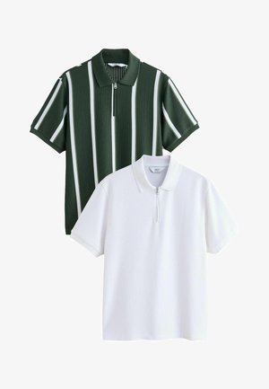 Deux polos à manches courtes, l'un en blanc uni et l'autre vert foncé avec des rayures blanches verticales, tous deux avec une texture côtelée et des cols zippés à l'avant.