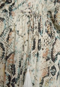 Robe à coupe décontractée en tissu léger avec un imprimé serpent multicolore, taille cintrée et détail en tresse blanche au niveau de la fermeture à cordon.