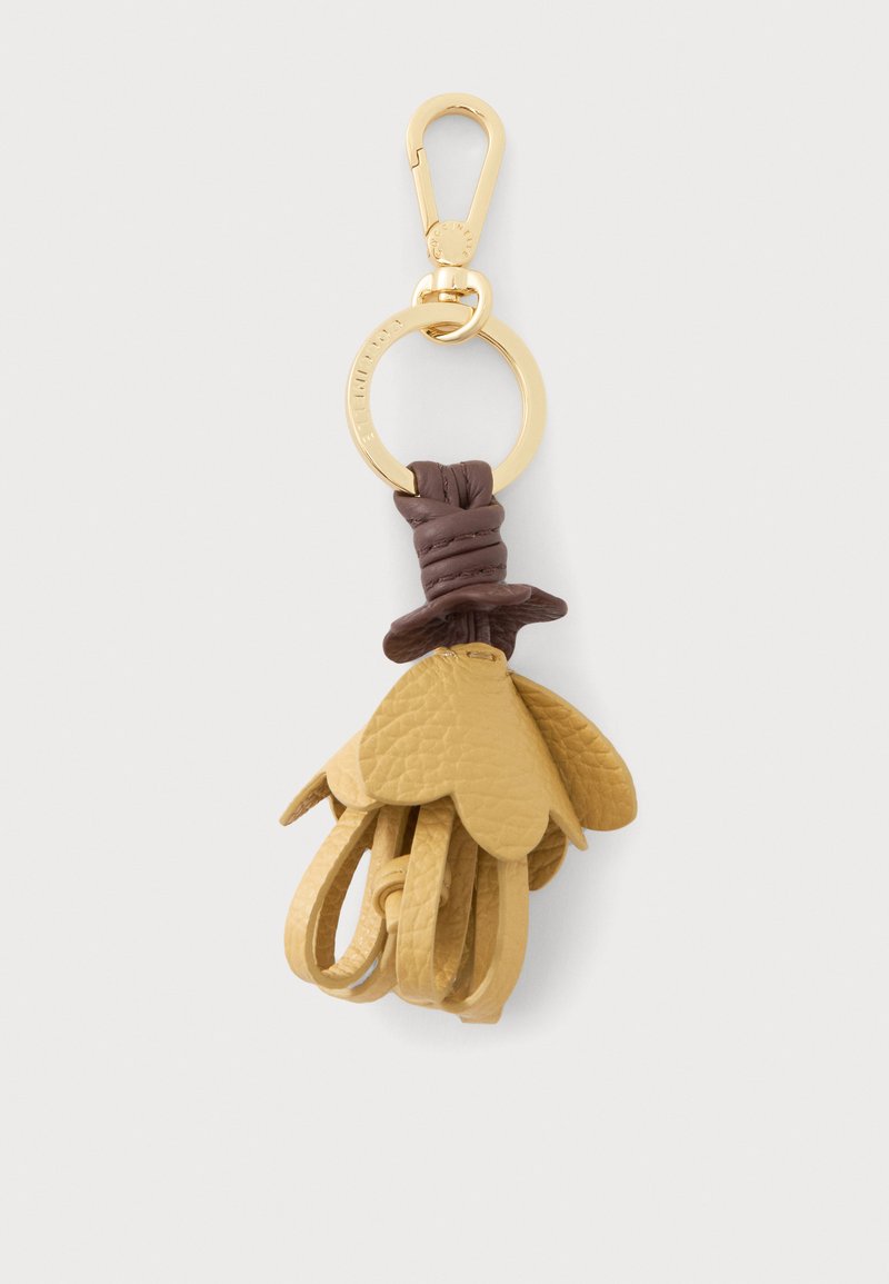 Porte-clés en métal doré avec un nœud en cuir marron et plusieurs pampilles en cuir beige texturé ressemblant à des pétales de fleurs.