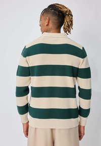 Polo en tricot rayé vert et crème avec une texture côtelée et des manches longues, doté d'un col classique et d'un ourlet droit.