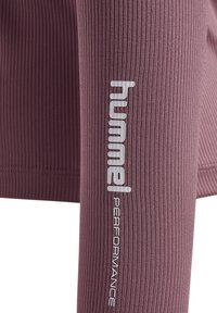Langarmhemd aus mauvefarbenem Rippmaterial mit einem weißen Logo-Akzent und dem Text "PERFORMANCE" entlang des Arms.