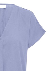 Blouse courte à manches courtes de couleur violet clair, avec un col en V et une coupe ample, présentée sur un fond blanc.