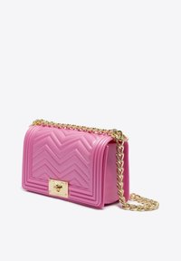 Borsa a tracolla trapuntata rosa brillante con design a zigzag, dotata di una catena dorata e di una chiusura dorata, collocata su uno sfondo semplice.