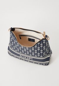 Navy-mønstret tote bag med blomsterdesign, gyldent hardware og et rummelig interiør. Har en lynlås lomme og "JOOP!" branding på fronten.