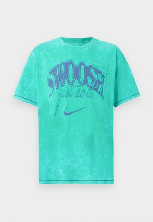 Majica mint zelene boje, prevelika, s izbjeljenom teksturom. Ima odvažno ljubičasto "SWOOSH" grafičko obilježje s natpisom "just do it" i Nike logotipom.