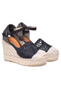 Espadrilles compensées bleu marine avec une tige en tissu tissé, une semelle intérieure en cuir tan et une semelle intermédiaire en jute tressé. Bride de cheville réglable avec détail de boucle.