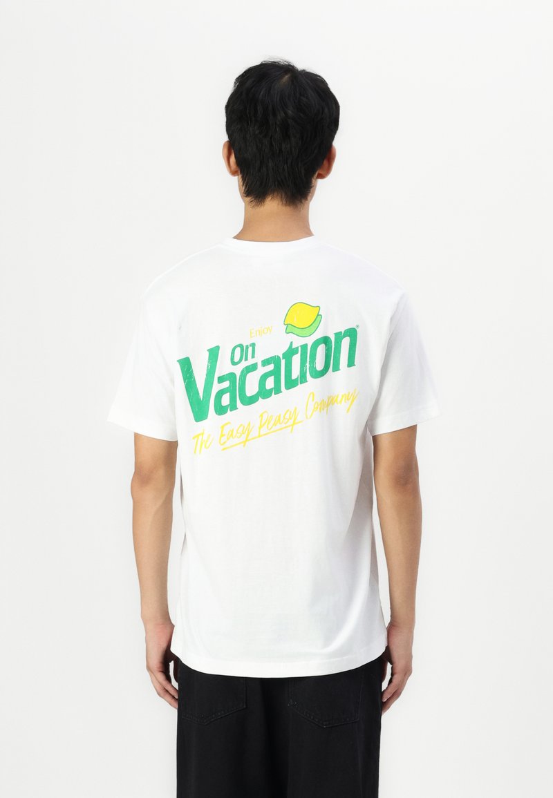 White cotton t-shirt featuring green and yellow text on the back: "Enjoy Vacation" with a lemon graphic and "The Easy Peasy Company."