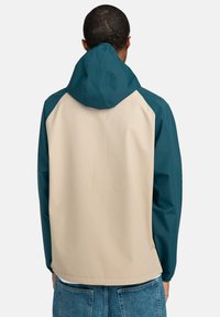 Inpakbare gevoerde jas met beige en teal panelen, met een gladde textuur, elastische boorden en een losse pasvorm.