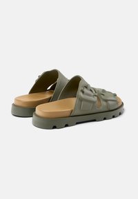 Green rubber slide sandals with a textured upper, open design, and tan footbed. Features pronounced tread on the sole for grip.