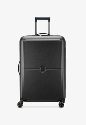 Valigia rigida nera con una texture liscia, manico estensibile e quattro ruote. Dettaglio del logo rotondo centrato sul pannello anteriore.