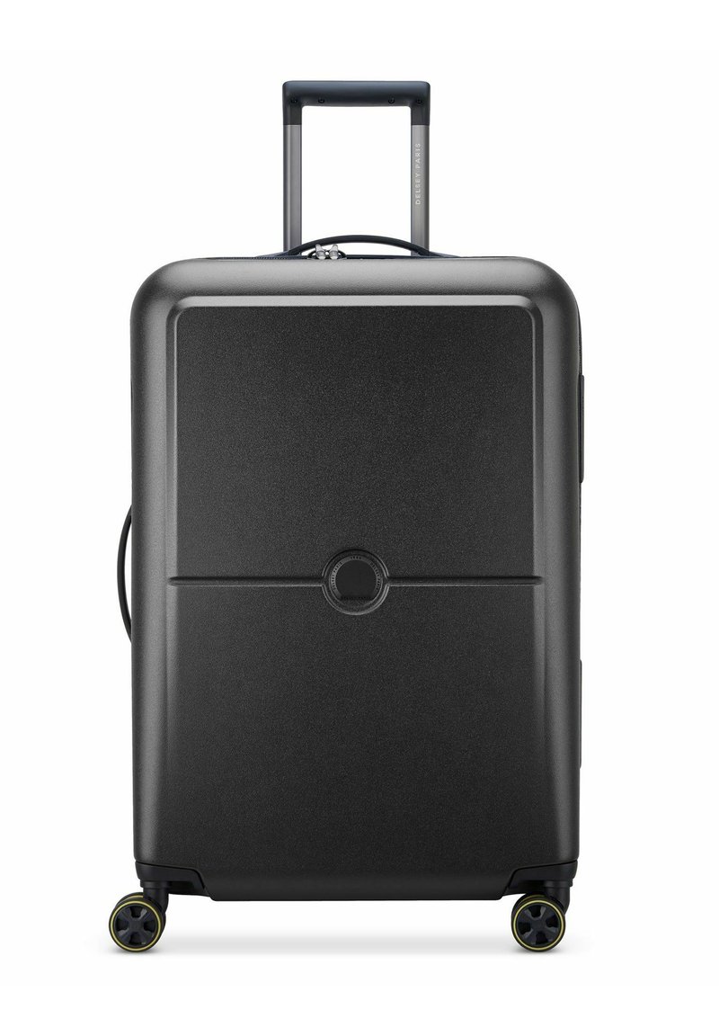 Valigia rigida nera con una texture liscia, manico estensibile e quattro ruote. Dettaglio del logo rotondo centrato sul pannello anteriore.