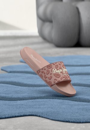 Sandalia de diapositiva rosa con tira de estampado de leopardo y logo blanco "Pepe Jeans London" sobre alfombra azul texturizada, con una gran escultura abstracta gris al fondo.