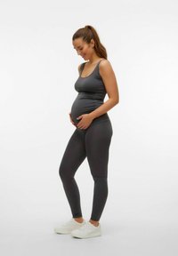 Gravidkläder i mörkgrått, bestående av en figurnära linne och leggings, mjuk textur, kombinerat med vita sneakers.