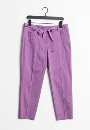 Pantalon lavande fuselé avec poches avant et ceinture en tissu nouée en nœud, suspendu à un cintre en plastique noir sur fond blanc.