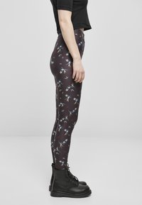 Leggings ajustés à imprimé floral noir, avec un fond sombre et des motifs de fleurs colorés. Assortis à des bottes noires à lacets.