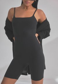 Body senza maniche nero con scollatura quadrata, forma aderente e design simile a pantaloni da ciclismo. Texture morbida con dettagli di cucitura minimal.
