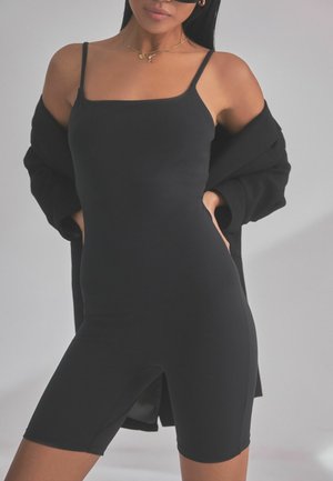 Sort ærmeløs bodysuit med firkantet halsudskæring, tætsiddende pasform og design som cykelshorts. Blød tekstur med minimale syninger.