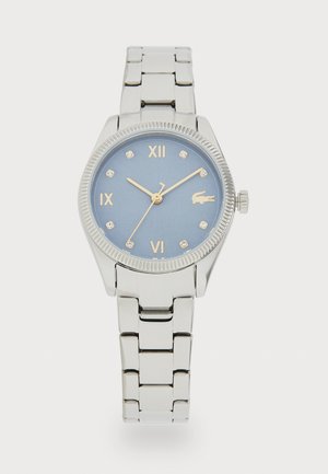Montre en métal argenté avec un cadran bleu, des chiffres romains, des marqueurs d'heure en cristal Swarovski et un bracelet en acier inoxydable. Accents dorés sur les aiguilles.
