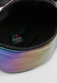Rund pouch med en metallisk iriserende finish, lynlåslukning og sort stofforing. Brandmærke synligt indeni.