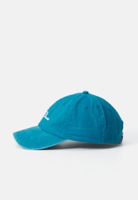 Blue soft fabric baseball cap with curved brim and white embroidered script on front side, displayed on white background.
