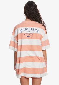 Krátkosrsté oversized tričko s horizontálními oranžovými a bílými pruhy, s logem "Quiksilver" potištěným na zadní straně v námořnické modři.