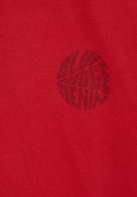 Sarkans kokvilnas T-krekls ar melnu grafisko logotipa dizainu, kas ietver izliekta teksta un līniju elementus. Gluda tekstūra, standarta piegriezums.