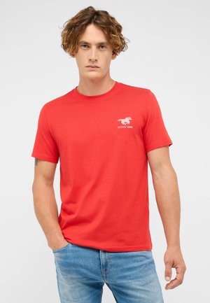 Red cotton t-shirt with short sleeves, round neckline, and a white horse logo on the left chest. Worn with light blue denim jeans.