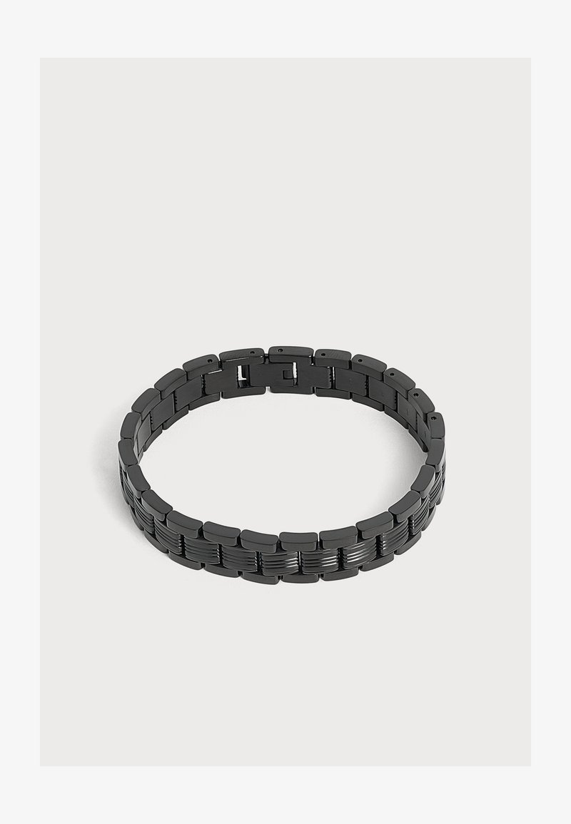 Bracelet à maillons en métal noir avec des segments rectangulaires légèrement incurvés et un fermoir caché, présenté sur un fond gris clair.