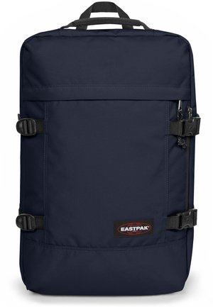 Mochila de color navy con forma rectangular, fabricada con un tejido resistente. Cuenta con correas ajustables, un asa en la parte superior y un parche con la marca.