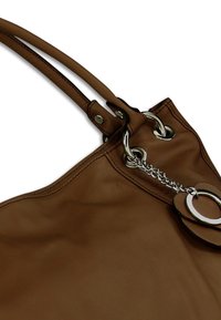 Bruine leren shopper met twee handvatten, voorzien van een zilverkleurig metalen accent, kettingdetail en een cirkelvormige versiering bij de sluiting.
