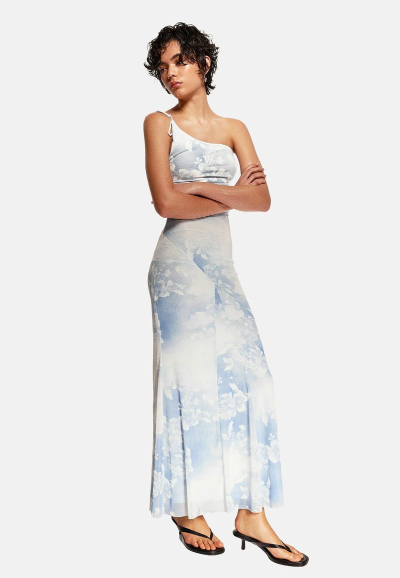 Ett tvådelat set bestående av en ljusblå blommig crop top med spagettiband och en matchande lång kjol med veck och en flytande design.