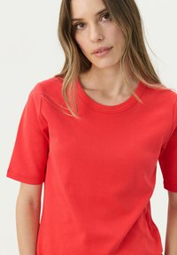 T-shirt rouge à manches courtes en tissu coton avec un col rond et une texture lisse. Présente des coutures impeccables et une coupe classique.
