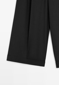 Schwarze, weit geschnittene Hose aus glattem Stoff mit sauberem Saum und dezenten Falten. Keine sichtbaren Verschlüsse oder Taschen vorhanden.
