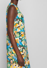Vestido sin mangas con estampado floral en colores azul, amarillo y verde, con una forma A-line relajada y un vibrante patrón multicolor.