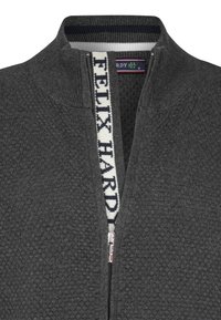 Dunkelgrauer Reißverschluss-Pullover mit strukturiertem Design, ausgestattet mit einem weiß-blauen gestreiften Kragen und einem sichtbaren Reißverschluss mit Branding auf dem Band.