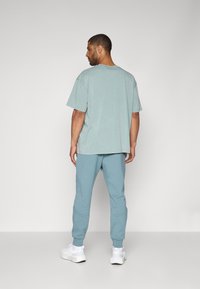 Under Armour UNSTOPPABLE FLEECE - Tracksuit bottoms - jasper blue/serpentine/black