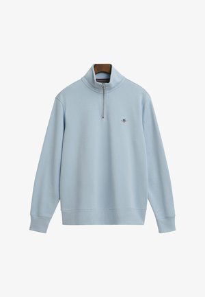 Lys blå zip-up sweatshirt med høj krave, blød stoftekstur, ribbede manchetter og kant, med et lille logo på brystet.